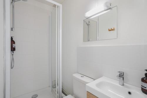 La salle de bains blanche est pourvue d'une douche et d'un lavabo. dans l'établissement BALCON DU CANAL - Studio lumineux avec balcon au bord de la Vilaine et de lhyper centre-ville, à Rennes