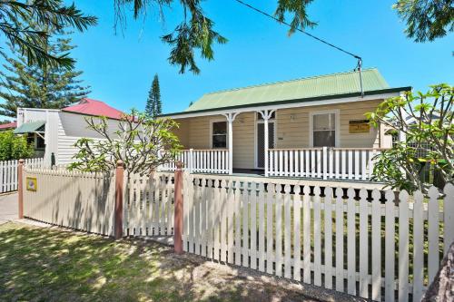 a white picket fence in front of a house at PJ's Cottage - Bring your own linen. in South West Rocks