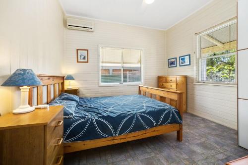 a bedroom with a bed and a desk and window at PJ's Cottage - Bring your own linen. in South West Rocks