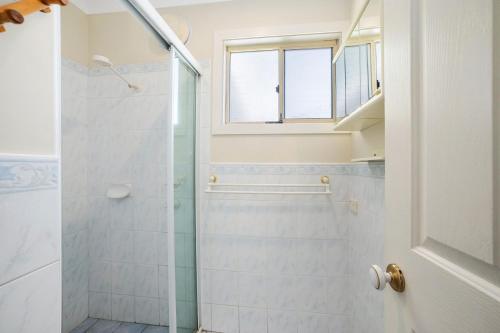 a bathroom with a shower with a glass door at PJ's Cottage - Bring your own linen. in South West Rocks