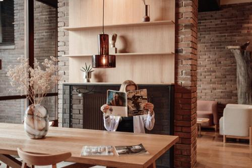 a woman is holding up a picture in front of a fireplace at Forest Hotel in Kraków