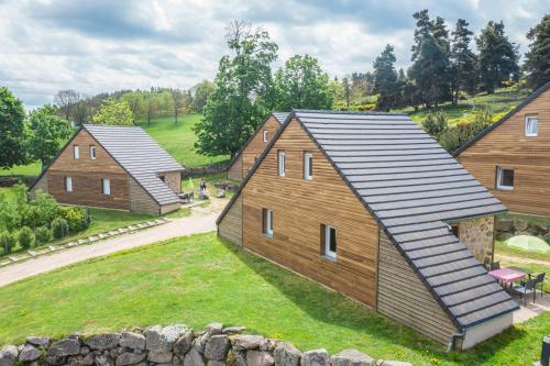 grupa drewnianych domów na polu w obiekcie Village de gîtes Les Chalets de l'Aubrac w mieście Aumont-Aubrac