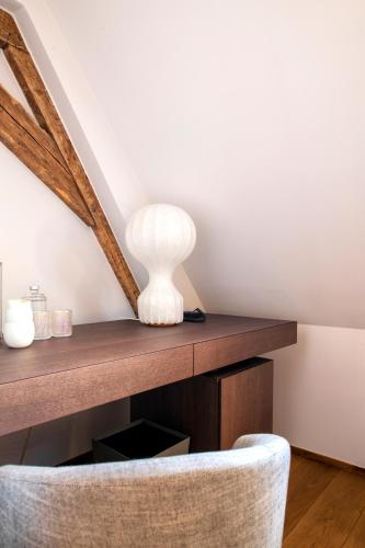 a white vase on a wooden table with a chair at Chateau de Wallerand in Vireux-Wallerand