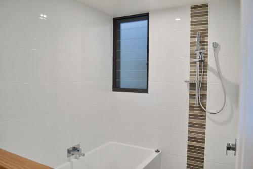 a white bathroom with a shower and a window at Rockleigh in South West Rocks