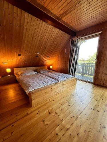 a bed in a wooden room with a large window at Ferienhaus Odenwald in Michelstadt