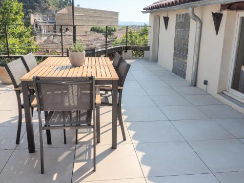 une table et des chaises en bois sur une terrasse dans l'établissement Le Rooftop - Vue incroyable sur le Théatre Antique, à Orange