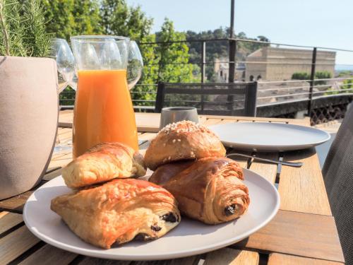 um prato de pastelaria numa mesa com um copo de sumo de laranja em Le Rooftop - Vue incroyable sur le Théatre Antique em Orange