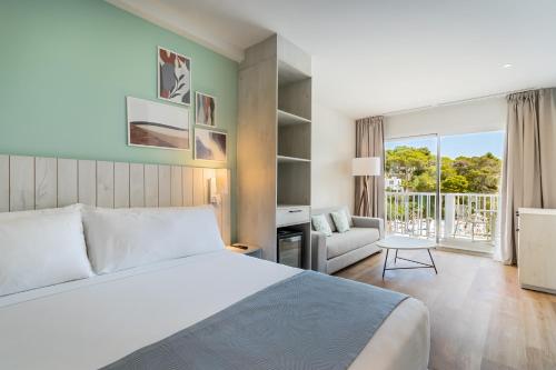um quarto com uma cama, um sofá e uma janela em Barceló Aguamarina em Cala d´Or