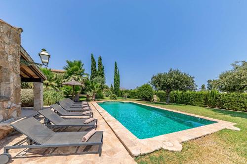 a swimming pool with lounge chairs next to a house at Villa Can Paroya in Alcudia