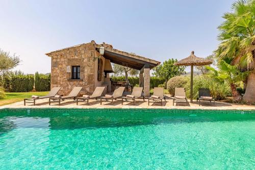 a swimming pool with chairs and a house at Villa Can Paroya in Alcudia