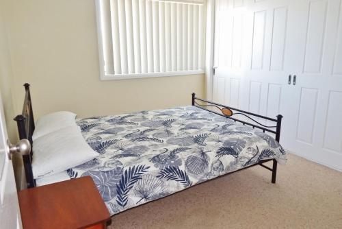 a bedroom with a bed with a blue and white blanket at Village Centre 3 South West Rocks in South West Rocks