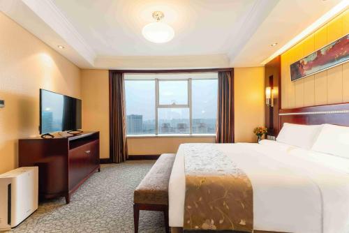 a hotel room with a large bed and a television at Yun-Zen Century Hotel in Shijiazhuang