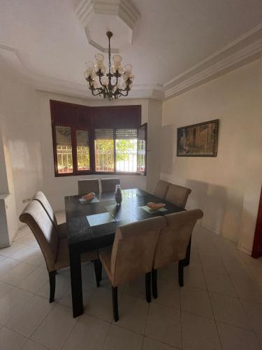 a dining room with a table and chairs and a chandelier at Mehdia Ville in Plage de Mehdia