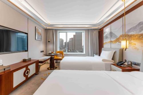 a hotel room with two beds and a television at Yun-Zen Century Hotel in Shijiazhuang