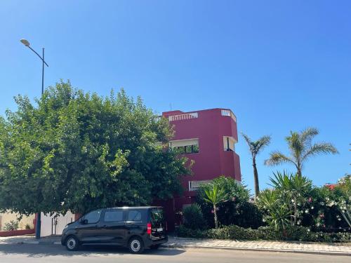 a black suv parked in front of a red building at Mehdia Ville in Plage de Mehdia