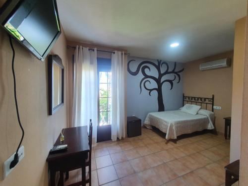 a bedroom with a bed and a tv and a window at POSADA LOS PEDREGALES in El Granado