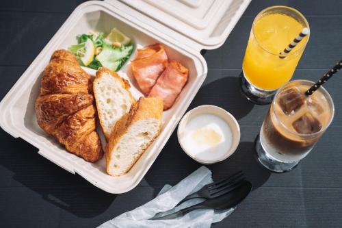 a tray of food with bread and fruit and a drink at てんとうみ 渋川海岸グランピング Tentoumi Shibukawa Beach Glamping in Tamano