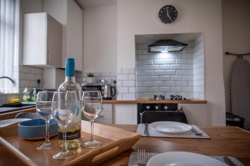 a bottle of wine and two wine glasses on a table at Tropicana House in Barnsley