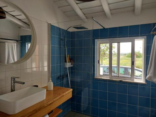 baño de azulejos azules con lavabo y ventana en Casa Azul do Cerro en Campeiros