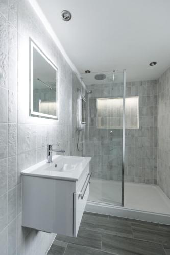 a white bathroom with a sink and a shower at The Granary in Swansea