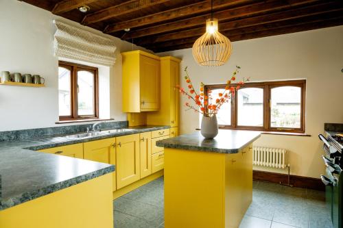 a kitchen with yellow cabinets and a vase with flowers at The Granary in Swansea