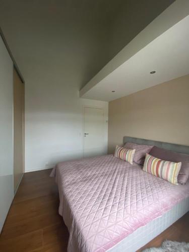 een slaapkamer met een groot bed met roze lakens en kussens bij Søbyen in Skanderborg