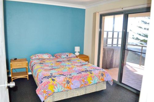 a bedroom with a bed and a blue wall at Northpoint Apartment 5 in South West Rocks