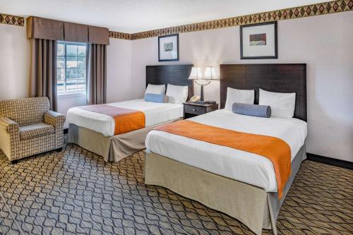 una habitación de hotel con 2 camas y una silla en Howard Johnson by Wyndham Lenox, en Lenox
