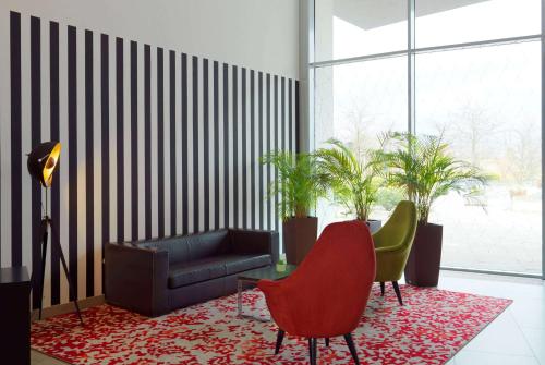 - un salon avec un canapé et des chaises sur un tapis dans l'établissement Ramada by Wyndham Dresden, à Dresde