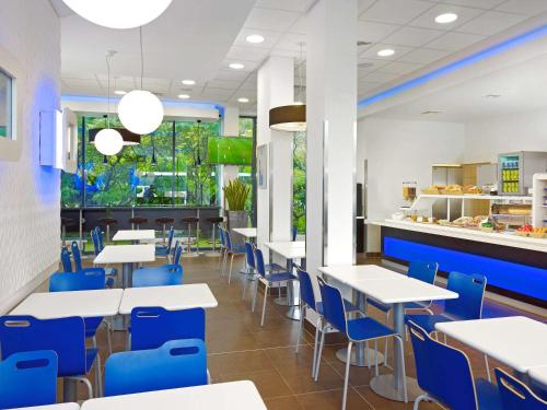 ワルシャワにあるibis budget Warszawa West Stationの白いテーブルと青い椅子が備わるカフェテリア