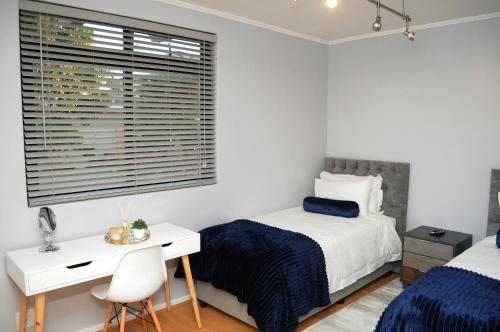 a bedroom with two beds and a desk and a window at Luxury 2 bedroom apartment in Cape Town in Cape Town