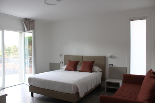 a white bedroom with a bed and a couch at Tennis Rocchette Resort in Castiglione della Pescaia