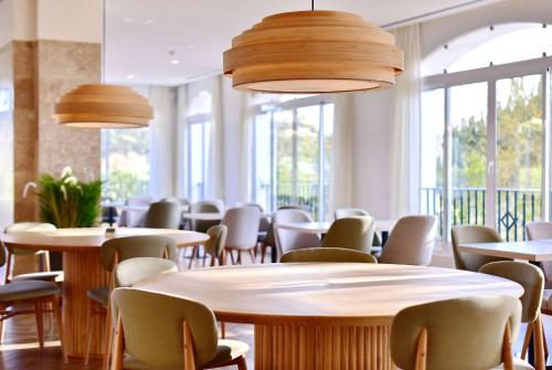 a row of tables and chairs in a room with windows at Dolce CampoReal Lisboa in Turcifal