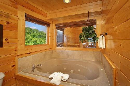 een badkamer met een bad in een houten cabine bij Kiss The Clouds - loft with a king bed in Sevierville
