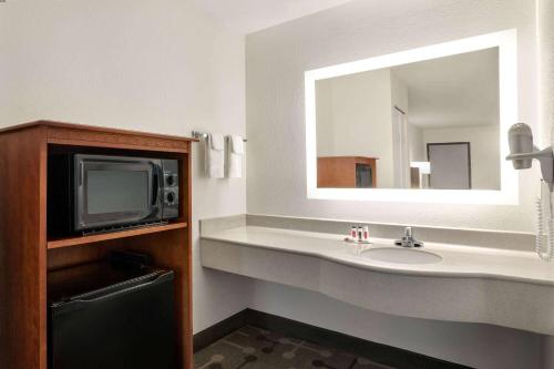 baño con lavabo, TV y espejo en Howard Johnson by Wyndham Chattanooga Lookout Mountain, en Chattanooga