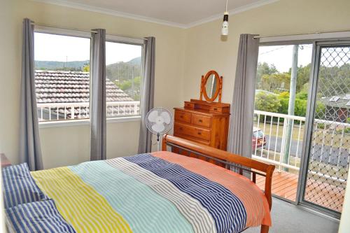 a bedroom with a bed and a balcony at Spencers Cottage in South West Rocks