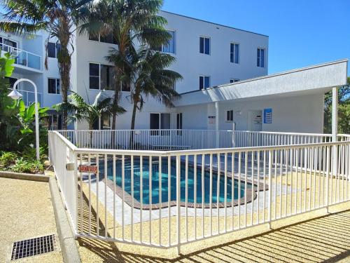 a white fence around a swimming pool in front of a building at Ocean Shores Apartment 17 - Bring you own linen. in South West Rocks