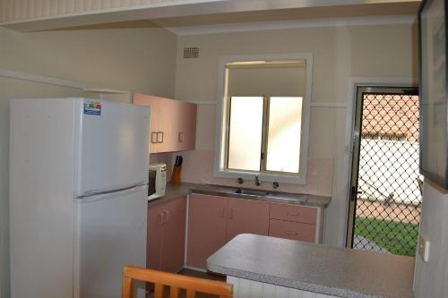 a kitchen with a white refrigerator and a sink at Clarkes Flat 1 in South West Rocks