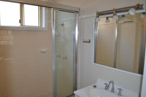 a bathroom with a shower and a sink and a mirror at Clarkes Flat 1 in South West Rocks