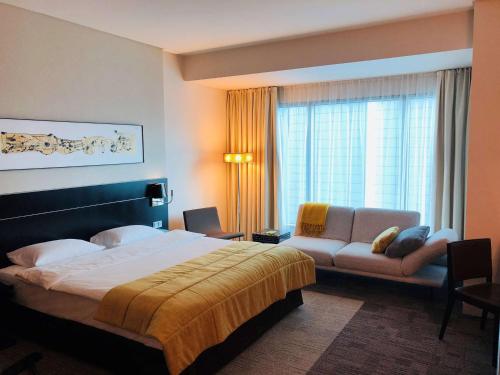 ein Hotelzimmer mit einem Bett und einer Couch in der Unterkunft Andersia Hotel & Spa Poznan, a member of Radisson Individuals in Posen