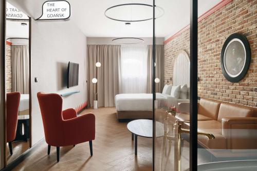 Radisson RED Gdansk, Wyspa Spichrzów في غدانسك: غرفة في الفندق مع أريكة وغرفة نوم
