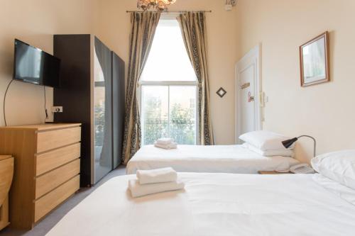 two beds in a room with a tv and a window at Amber Residence Hotel-Suites in London