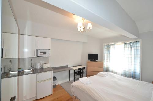 a bedroom with a bed and a kitchen with a desk at Amber Residence Hotel-Suites in London