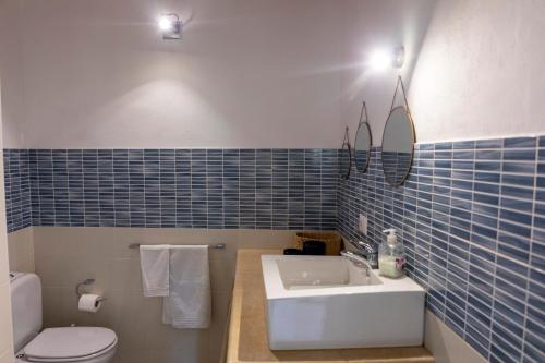 W wyłożonej niebieskimi kafelkami łazience znajduje się umywalka i toaleta. w obiekcie Casale Carratois - casa vacanze - Marzameni - Noto w mieście Portopalo