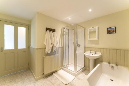 a bathroom with a shower and a tub and a sink at Garden Cottage in Gargunnock