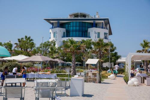 a building on the beach with tables and chairs at Blu Suite Resort in Bellaria-Igea Marina
