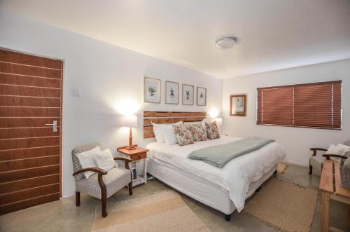 a bedroom with a large bed and a chair at Kariza in Yzerfontein