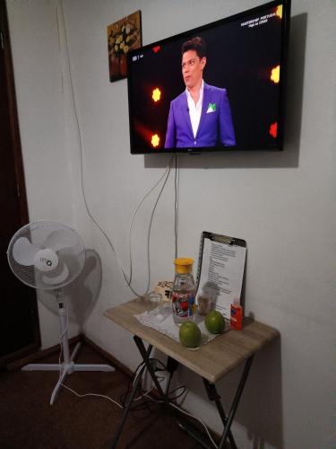 a tv on a wall with a table with fruit on it at Alojamento Local Largo da Igreja in Santiago do Cacém