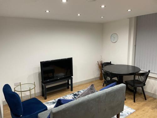 ein Wohnzimmer mit einem Sofa, einem Tisch und einem TV in der Unterkunft Modern - two bed - apartment located in the city of Wolverhampton in Wolverhampton