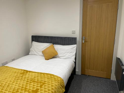 a bed with a yellow blanket next to a door at Modern - two bed - apartment located in the city of Wolverhampton in Wolverhampton